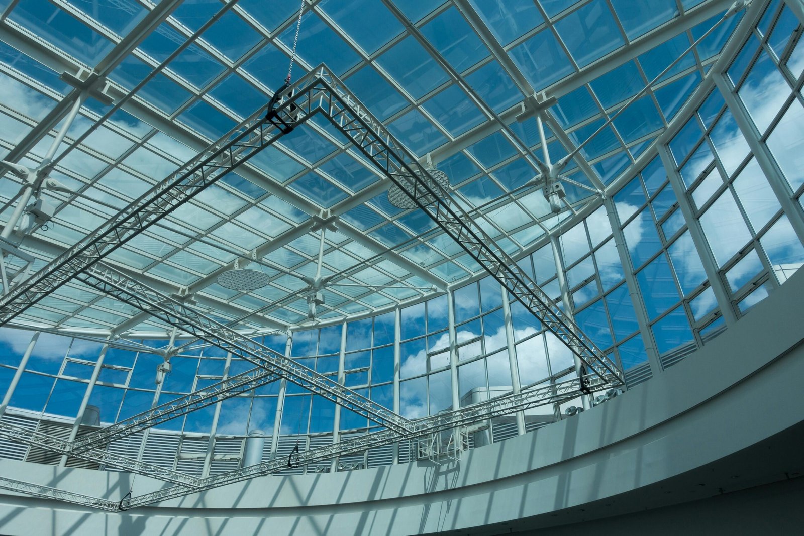 A modern indoor glass dome structure with steel design and a view of the blue sky.